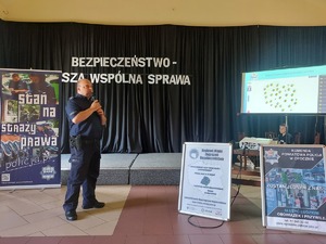Debata Społeczna w Białaczowie policjanci stoją za nimi napis Bezpieczeństwo nasza wspólna sprawa w tle na krzesłach siedzą mieszkańcy gminy