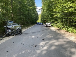 rozbite samochody na drodze, w tle radiowóz policji