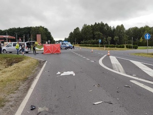 miejsce wypadku drogowego w Grębenicach, policjant idzie do parawanu, w tle radiowóz, na drodze rozstawione parawany policjanci wykonują oględziny miejsca wypadku