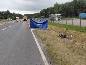 miejsce wypadku drogowego w Grębenicach, policjant idzie do parawanu, w tle radiowóz, na drodze rozstawione parawany policjanci wykonują oględziny miejsca wypadku