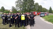 Policjanci, strażacy zbiórka przed poszukiwaniami zaginionego- wieś na terenie gminy Sławno powiat opoczyński. W tle wozy strażackie oraz radiowozy policyjne.