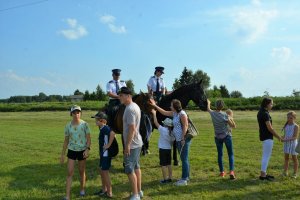 policjanci na koniach i obok ludzie  z pikniku