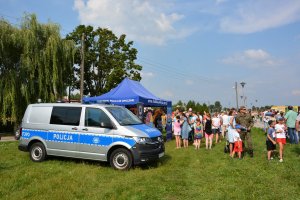 policyjny radiowóz na pikniku, w tle namiot policyjny i ludzie z pikniku