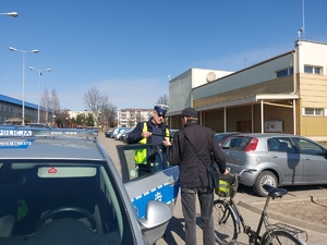 policjant rozdaje elementy odblaskowe  przedszkolakom i rowerzystom,