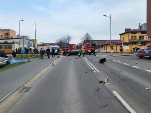 foto.1. rozbity czarny samochód, stoi na drodze foto 2 perspektywa miejsca kolizji w tle samochody słuzb ratunkowych straży policji, foto 3 rozbity szary samochód osobowy. foto 4 radiowoz policji, stoi tylem na ulicy