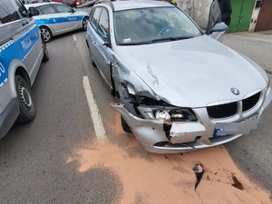 foto.1. rozbity czarny samochód, stoi na drodze foto 2 perspektywa miejsca kolizji w tle samochody słuzb ratunkowych straży policji, foto 3 rozbity szary samochód osobowy. foto 4 radiowoz policji, stoi tylem na ulicy