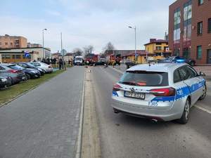 foto.1. rozbity czarny samochód, stoi na drodze foto 2 perspektywa miejsca kolizji w tle samochody słuzb ratunkowych straży policji, foto 3 rozbity szary samochód osobowy. foto 4 radiowoz policji, stoi tylem na ulicy