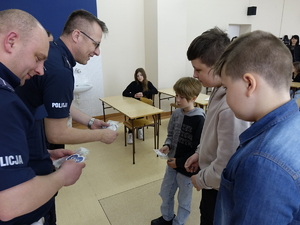 Policjanci podczas  turnieju BRD w szkole w Drzewicy. W klasie siedzą uczniowie, policjanci stoją przed nimi, Burmistrz i pracownica  urzędu  stoją obok