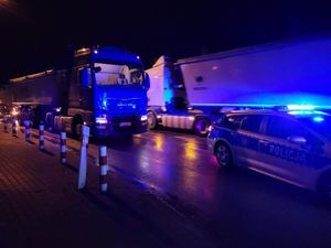 miejsce wypadku drogowego. W Żarnowie ulica  Szeroka. Na foto widać, radiowóz policji na sygnałach, za nim stoi na jezdni samochód ciężarowy z naczepą. W tle widać inny pojazd który jedzie przeciwnym pasem ruchu.