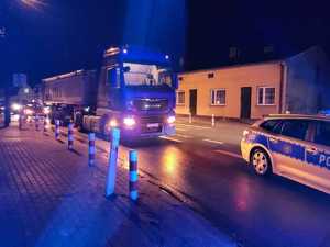 miejsce wypadku drogowego. W Żarnowie ulica  Szeroka. Na foto widać, radiowóz policji na sygnałach, za nim stoi na jezdni samochód ciężarowy z naczepą. W tle widać inny pojazd który jedzie przeciwnym pasem ruchu.