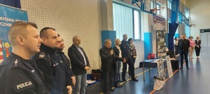 eliminacje powiatowe konkursu. Hala sportowa, zawodnicy ze szkół, stoją takze przedstawiciele władz samorządowych, kierownictwo policji, policjanci,  w tle widać stół z nagrodami oraz banery policji