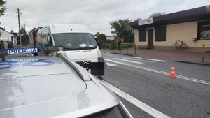 Policjanci podczas obsługi zdarzenia drogowego w Paradyżu Droga, na niej samochód w kolorze białym, na pierwszym planie radiowóz oznakowany oraz umundurowany policjant stojący tyłem
