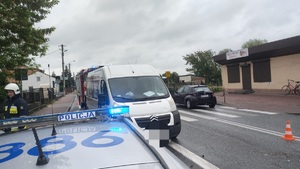Policjanci podczas obsługi zdarzenia drogowego w Paradyżu Droga, na niej samochód w kolorze białym, na pierwszym planie radiowóz oznakowany oraz umundurowany policjant stojący tyłem
