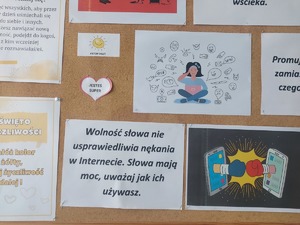 policjantka podczas spotkania z młodzieżą. stoi przodem do klasy. dzieci siedzą w ławkach. 
tablica informacyjna z plakatami  dotyczącymi przeciwdziałania hejtowi w Internecie. dzień życzliwości