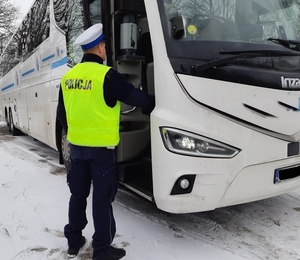 policjant stoi przed autobusem