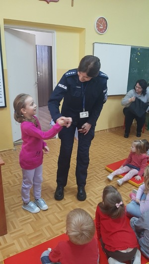 policjantka pochylona nad dzieckiem, rozmawiają, obok stoi kilkuletnia dziewczynka