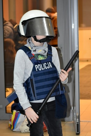 chłopiec ubrany w policyjną kamizelkę oraz kask