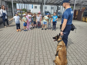 dzieci w komendzie policji, spotkanie z policjantami. Strzelnica policyjna, przewodnik psa służbowego, dzieci stoją policjanci stoją przodem do dzieci, rozmawiają, dzieci przed budynkiem komendy stoją na schodkach