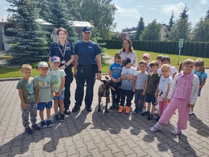 dzieci w komendzie policji, spotkanie z policjantami. Strzelnica policyjna, przewodnik psa służbowego, dzieci stoją policjanci stoją przodem do dzieci, rozmawiają, dzieci przed budynkiem komendy stoją na schodkach