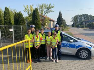 akcja jabłko cytryna.. dzieci i policjanci wręczają kierowcom cytrynę  policjanci stoją obok dzieci  kierowca przyjmuje plaster cytryny