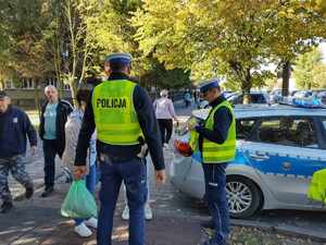 policjanci rozdają odblaski, stoją na ulicy wokół stoją ludzie