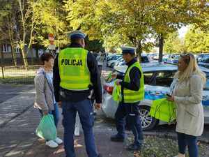 policjanci rozdają odblaski, stoją na ulicy wokół stoją ludzie