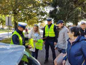 policjanci rozdają odblaski, stoją na ulicy wokół stoją ludzie