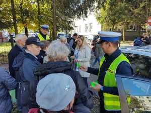 policjanci rozdają odblaski, stoją na ulicy wokół stoją ludzie