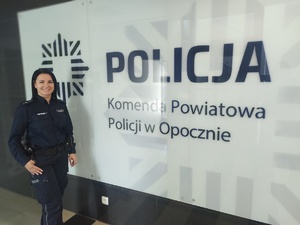 policjantka stoi przy ścianie z  napisem Komenda Powiatowa Policji w Opocznie