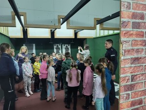 dzieci znajdują się na strzelnicy, obok stoi policjant i nauczycielka.