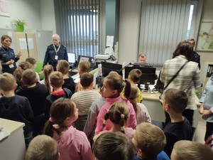 policjant i policjantka rozmawiają z dziećmi w służbowym pomieszczeniu.