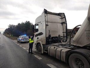 droga, policjantka stoi przy samochodzie ciężarowym.