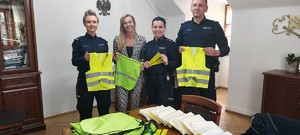policjanci i kobieta trzymają elementy odblaskowe.