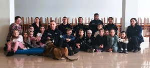 grupa ludzi, strażacy, policjanci, dzieci, pies służbowy.