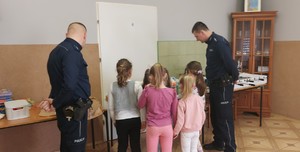 policjanci , dzieci oglądają prace plastyczne.