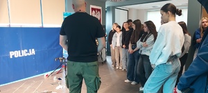 mężczyzna rozmawia z młodzieżą, w tle napis policja.