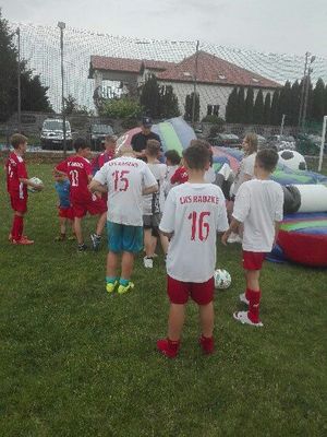 dzieci w strojach sportowych rozmawiają z policjantem, dmuchane zabawki.