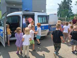 dzieci wchodzą do policyjnego radiowozu.