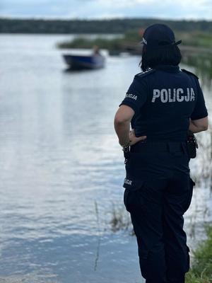 policjantka stoi nad brzegiem jeziora.