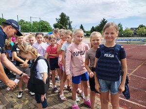 policjant, pokazuje wyposażenie policjantów, dziewczynka w kamizelce kuloodpornej.