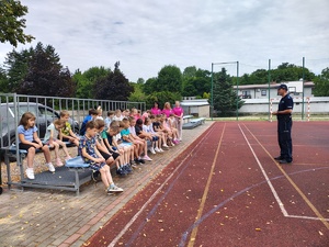 policjant rozmawia z dziećmi, widoczne trzy kobiety.