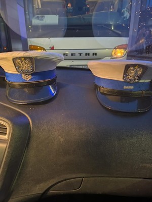 czapki policyjne w tle autobus.