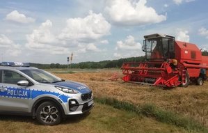 policyjny radiowóz i kombajn w polu.