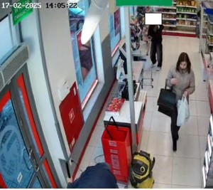 pomieszczenie sklepu, kobieta z czarną torebką, w drugiej ręce trzyma małą torebkę, za nią osoba ubrana na czarno.