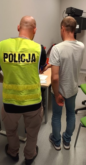 policjant w kamizelce odblaskowej z napisem policja i mężczyzna w szarej koszulce.