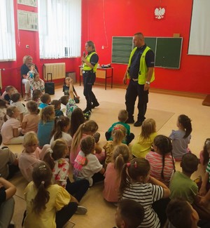 policjanci w kamizelkach odblaskowych rozmawiają z dziećmi.