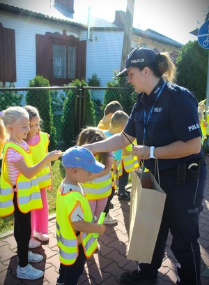 policjantka rozdaje odblaski dzieciom.