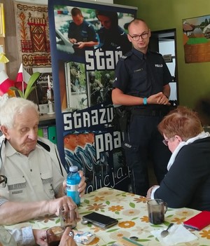 policjant rozmawia z seniorami.