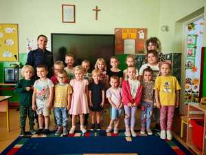 dzieci i policjanci, kobieta stoją na tle tablicy w klasie lekcyjnej.