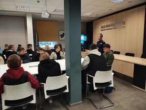 policjantka rozmawia z młodzieżą na sali konferencyjnej policji w Opocznie.